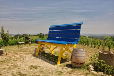 Lounge chairs and table on field against sky