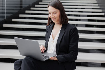 Young woman using laptop while sitting on sofa