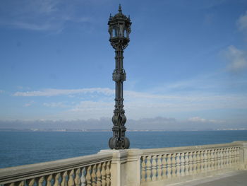 Lamp post on balustrade at promenade against blue sky