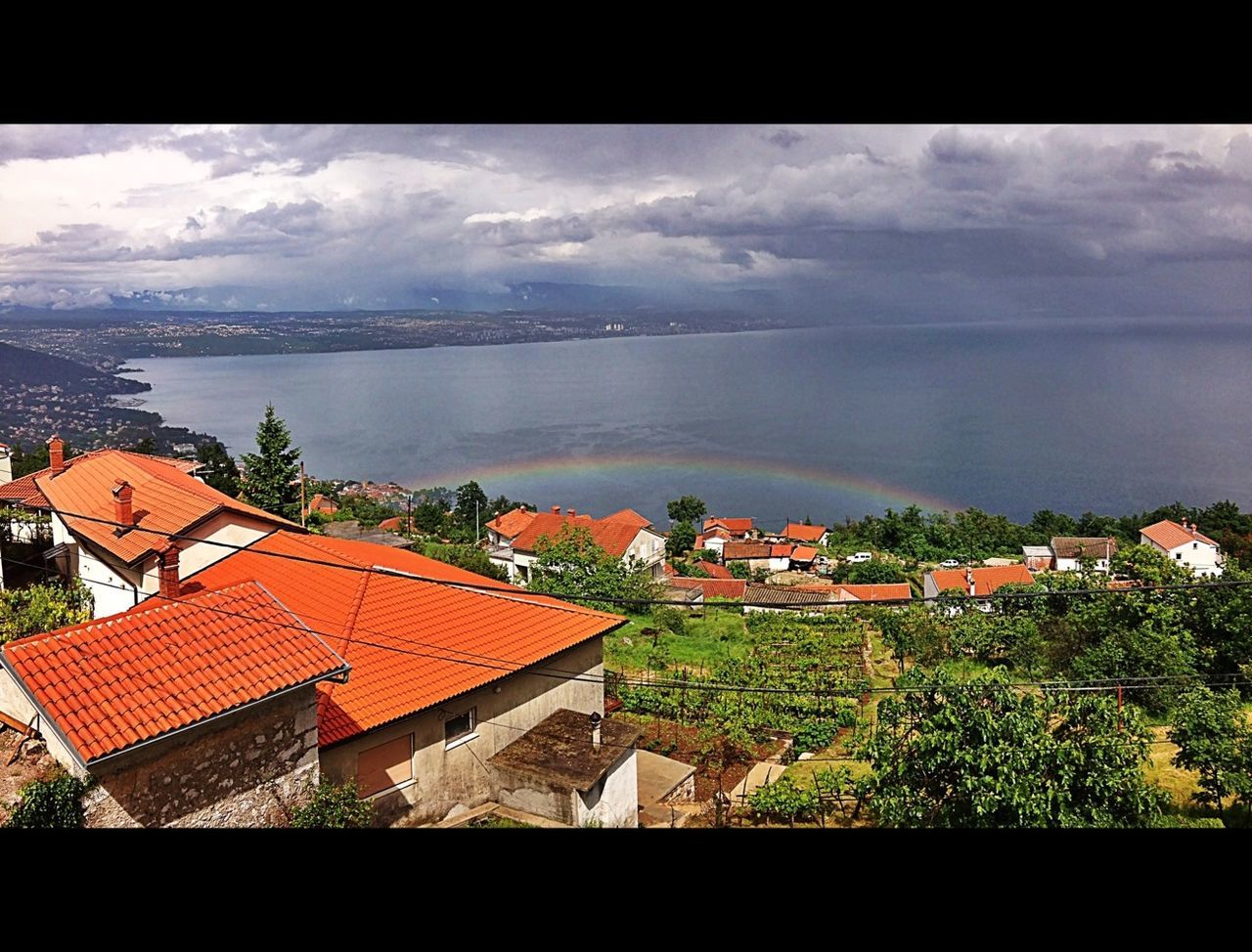 building exterior, architecture, built structure, roof, house, sky, residential structure, high angle view, town, residential district, townscape, water, residential building, sea, cloud - sky, cityscape, city, crowded, horizon over water, cloud