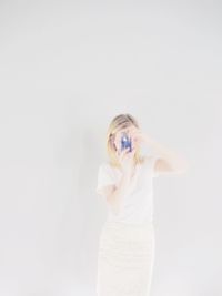 Young woman photographing against white background