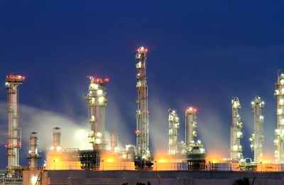 Illuminated factory against sky at night