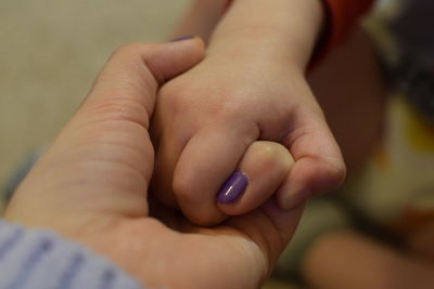 Close-up of woman holding son hand