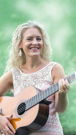 Portrait of a smiling young woman playing guitar