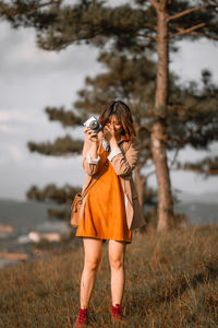 Full length of woman photographing on field