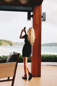 Full length of woman standing by sea against sky