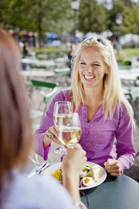 Two women toasting wine at outdoor cafe