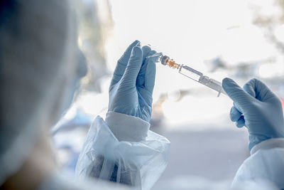 Cropped image of doctor holding syringe outdoors