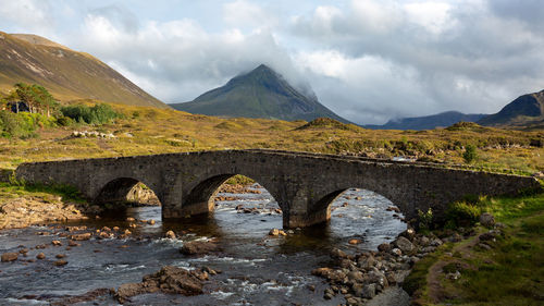 Arch bridge over mountains against sky