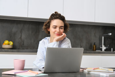 Portrait of young woman using laptop on table