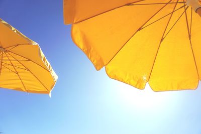 Low angle view of yellow umbrella against blue sky