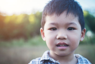 Close-up portrait of cute boy on field during sunny day