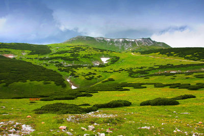 Scenic view of hill against cloudy sky