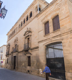 Rear view of man walking in front of historic building