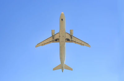 Low angle view of airplane against clear blue sky