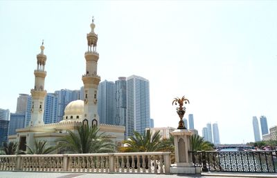 Statue of buildings in city against clear sky