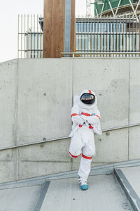 Male astronaut standing with arms crossed leaning on wall