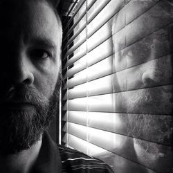 Double exposure image of bearded man by window blinds