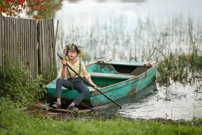 Portrait of boy sitting on boat by lakeshore