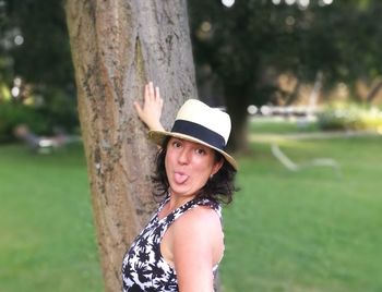 Portrait of smiling young woman against tree trunk