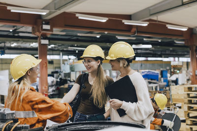 Smiling businesswomen discussing with female worker in factory