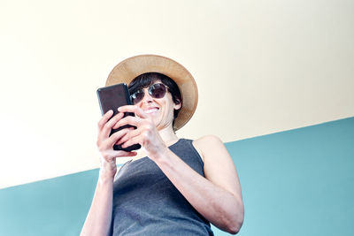 Portrait of man holding mobile phone against wall