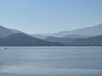 Scenic view of lake and mountains against clear blue sky