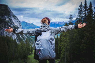 Rear view of woman with arms outstretched standing against mountain