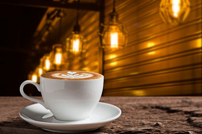 Close-up of coffee served on table with pendant lights hanging in background