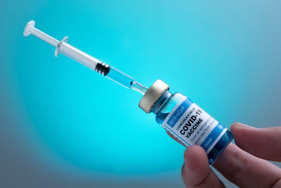 Close-up of hand holding blue against white background