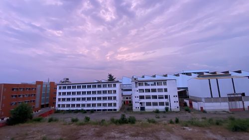 Buildings on field against sky at dusk