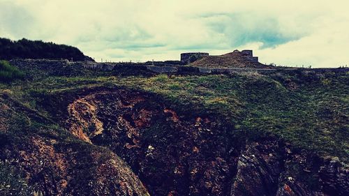 Built structure on landscape against cloudy sky