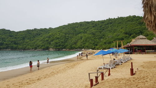 Group of people on beach against clear sky