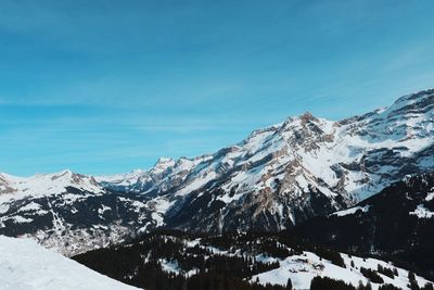 Scenic view of snowcapped mountains against blue sky