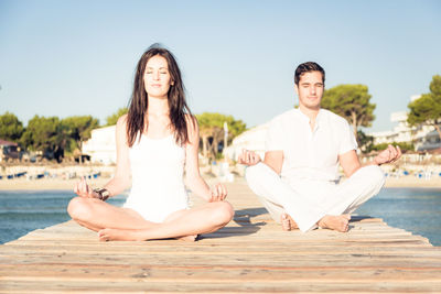 Portrait of young couple sitting on swimming pool