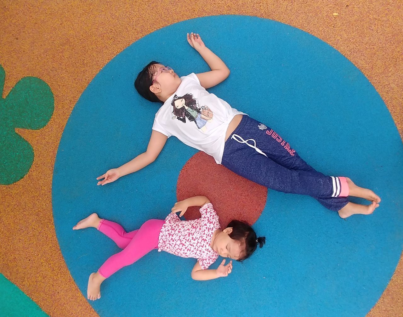 HIGH ANGLE VIEW OF SIBLINGS LYING DOWN ON FLOOR