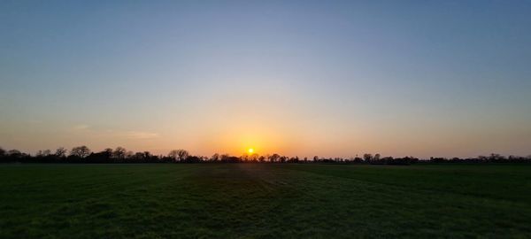 Scenic view of field against clear sky during sunset