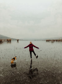 Woman standing in lake against sky