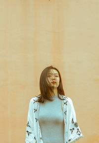 Young woman standing against wall