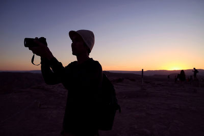 Silhouette man photographing at sunset