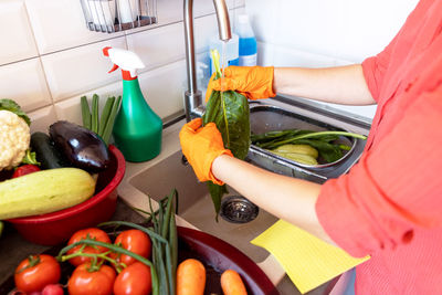 Washing fresh vegetables in the kitchen under cold running tap water