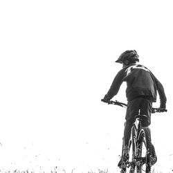 Rear view of man riding bicycle against clear sky