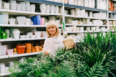 Gardening, planting and shopping concept. beautiful mature adult woman choosing houseplants and pots