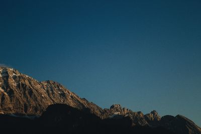 Low angle view of rocks against clear blue sky