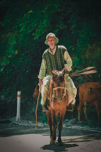 Senior man horseback riding against trees