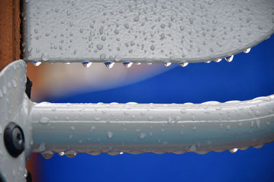 Close-up of water drops on glass against blue sky