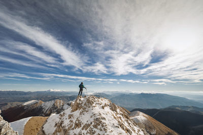 Man standing on snowcapped mountain against sky