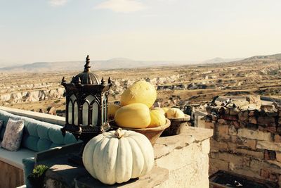 Pumpkins on retaining wall on building terrace against sky