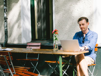 Young man using laptop while sitting on table