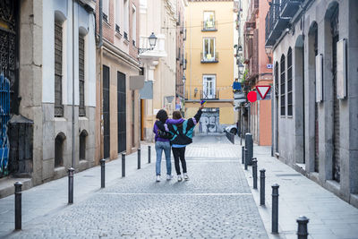 Two friends walking embraced outdoors on the street while holding an lgbt flag.